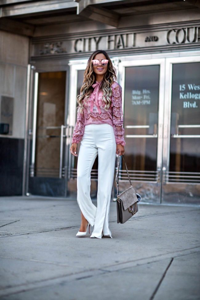 fashion blogger mia mia mine wearing a pink lace top from shopbop and white pants from revolve