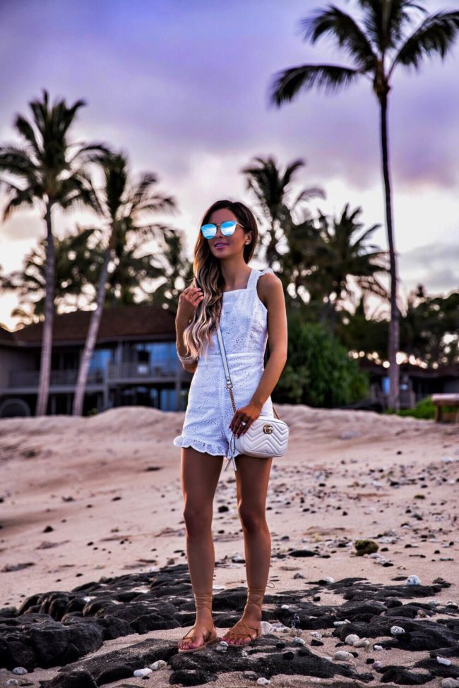 fashion blogger mia mia mine wearing a white eyelet romper at the four seasons hualalai on the big island at sunrise