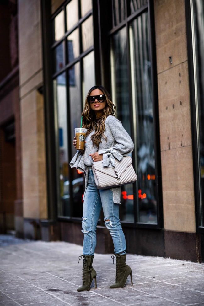 mia mia mine wearing a gray sweater and a saint laurent college bag