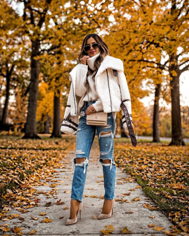 Fashion blogger mia mia mine wearing a shearling jacket and distressed denim jeans