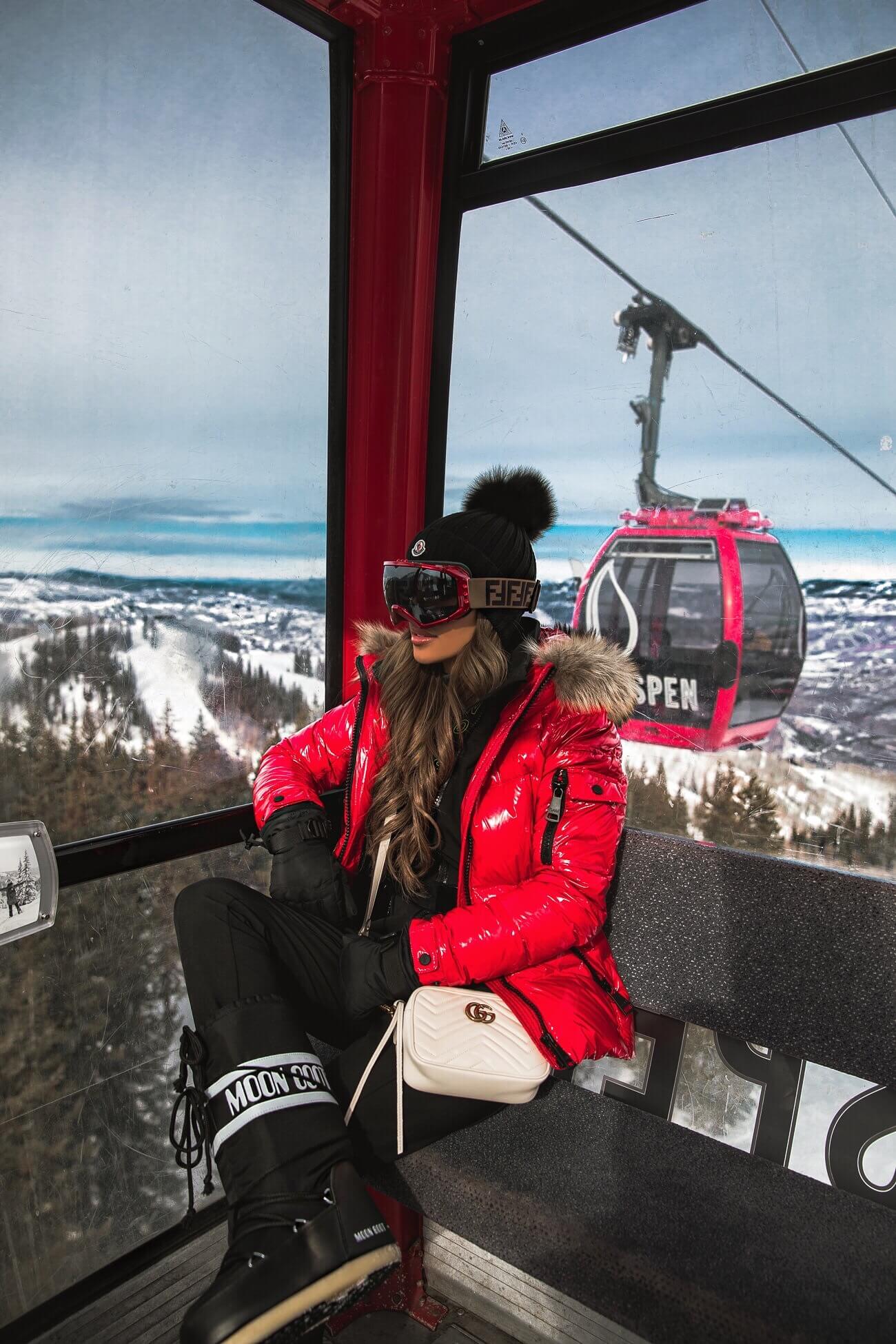 mia mia mine wearing a ski outfit on a gondola in aspen colorado