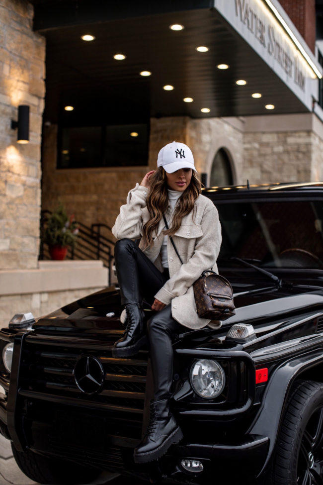 fashion blogger mia mia mine wearing a beige shirt jacket with the louis vuitton palm springs mini backpack