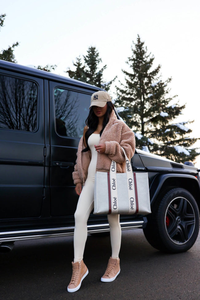 brunette fashion blogger wearing a white jumpsuit and tan nike blazer sneakers